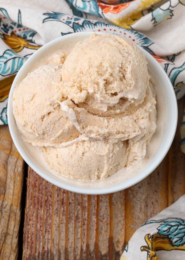 three scoops of ice cream in white bowl on wooden table