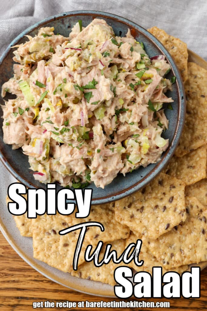 spicy tuna salad in a bowl with crackers and text overlay describing the photo