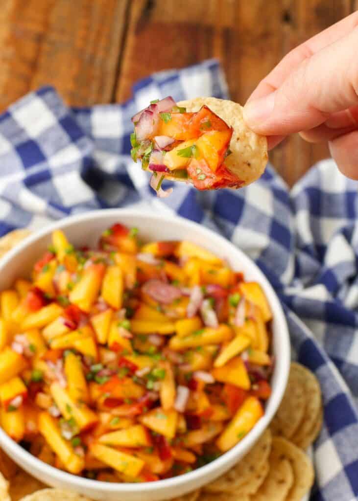 hand holding chip with a scoop of fruit salsa