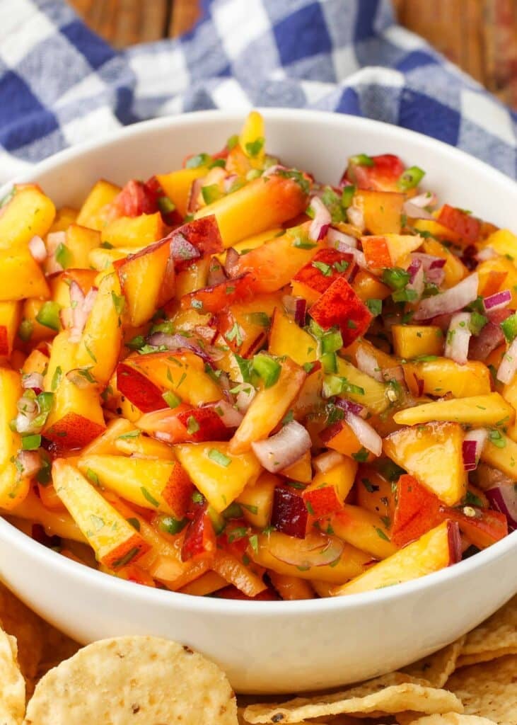 white bowl with peach jalapeno salsa next to chips