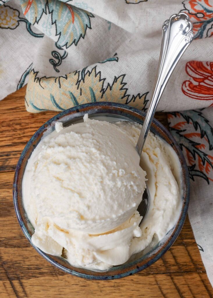 bowl of ice cream with silver spoon in it on wooden table