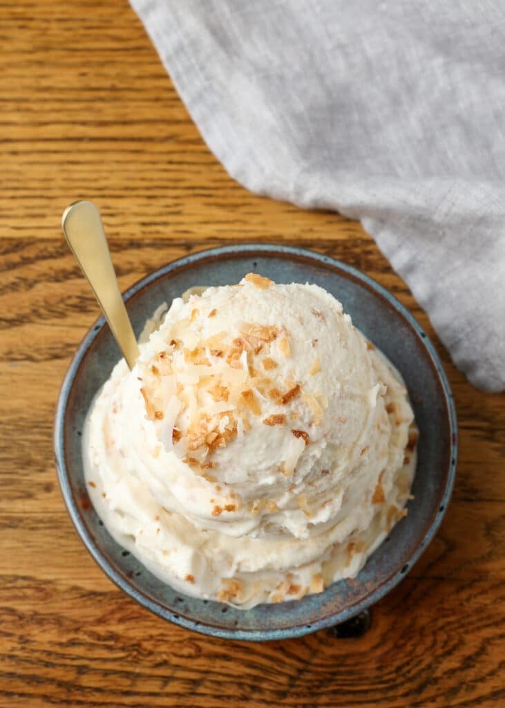 scoop of ice cream topped with toasted coconut in blue dish