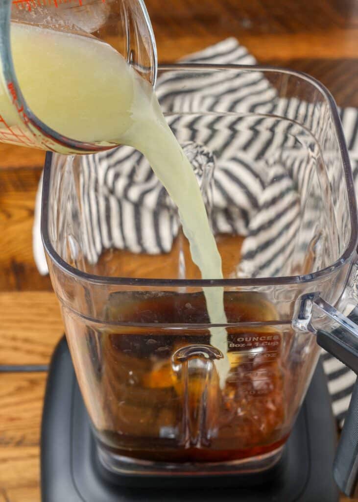 pouring ingredients for asian salad dressing in a blender