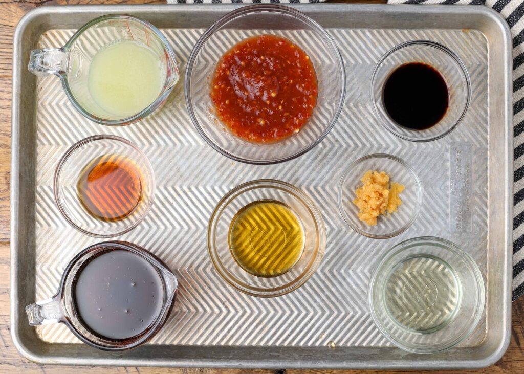 ingredients for asian salad dressing in small ramekins on a sheet pan