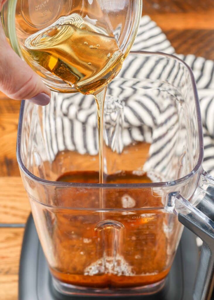 pouring ingredients for asian salad dressing in a blender