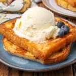 horizontal shot of french toast stacked on plate topped with scoop of ice cream