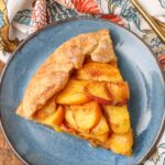 sliced peach dessert on blue plate with floral napkin