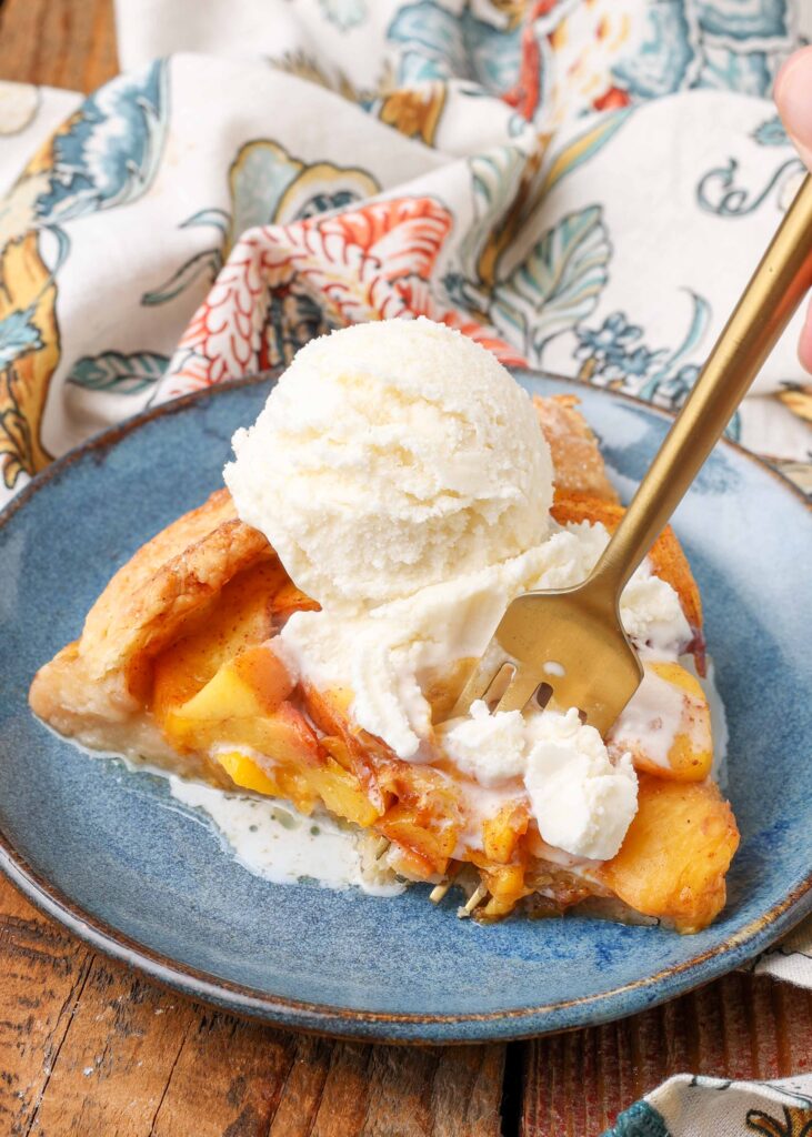 ice cream topped peach dessert with a gold fork