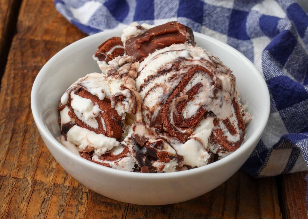 ice cream with Swiss Rolls and chocolate sauce in small white bowl