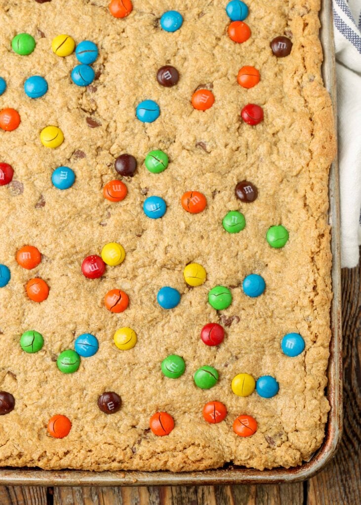 unsliced cookie bars topped with m&ms on sheet pan