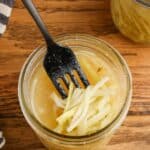 pickled broccoli stems in a jar of brine with a fork