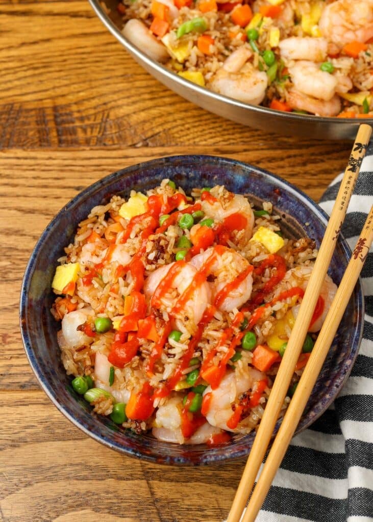 skillet of rice next to plated serving of fried rice with chopsticks