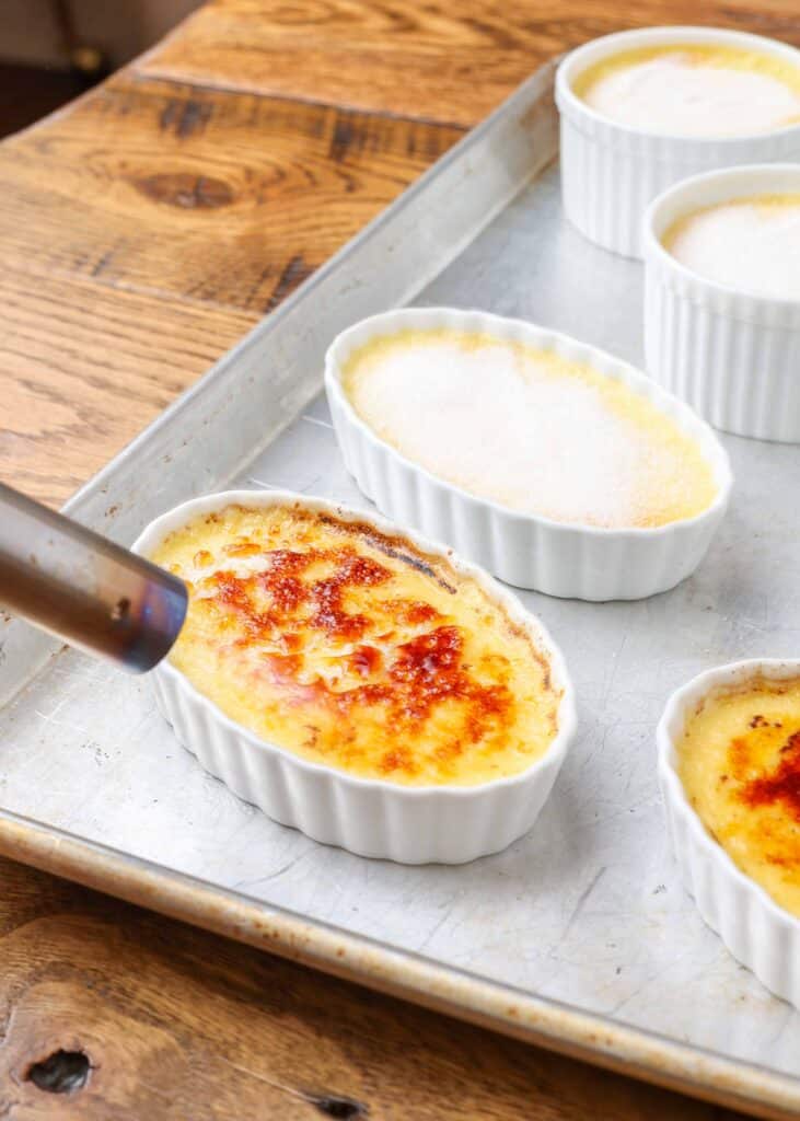 Creme brulee in a ramekin with torch caramelizing the sugar.