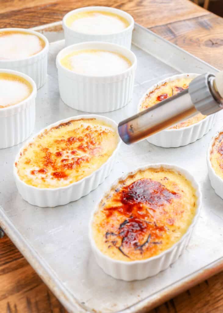 Creme brulee in a ramekin with torch caramelizing the sugar.