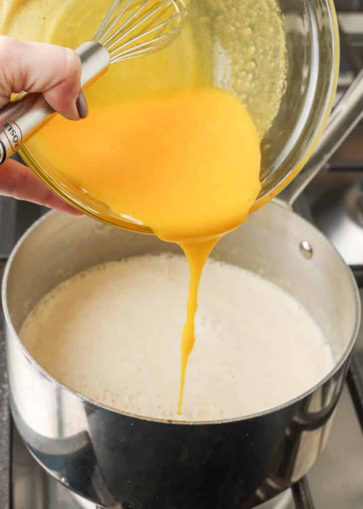Making custard by pouring egg yolks into hot cream.