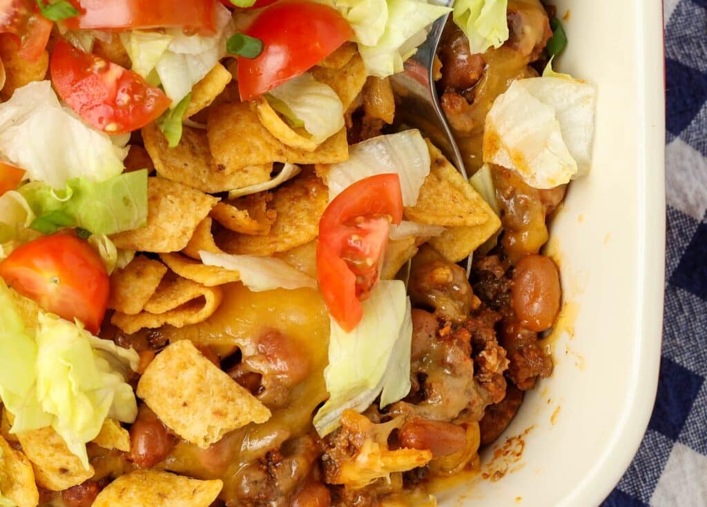 Frito pie casserole layered with lettuce and tomatoes