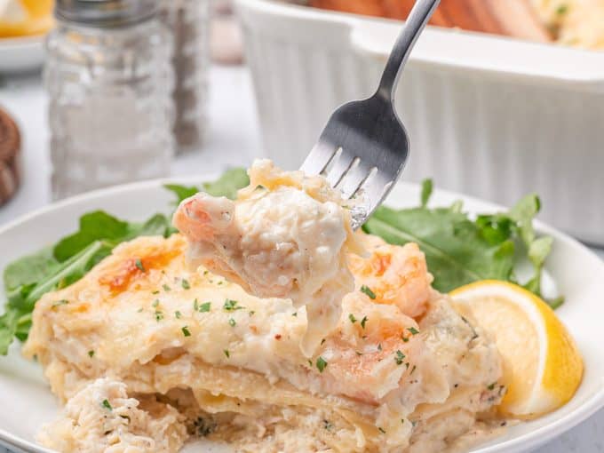 A bite of lasagna made with crab and shrimp in a bechamel sauce.