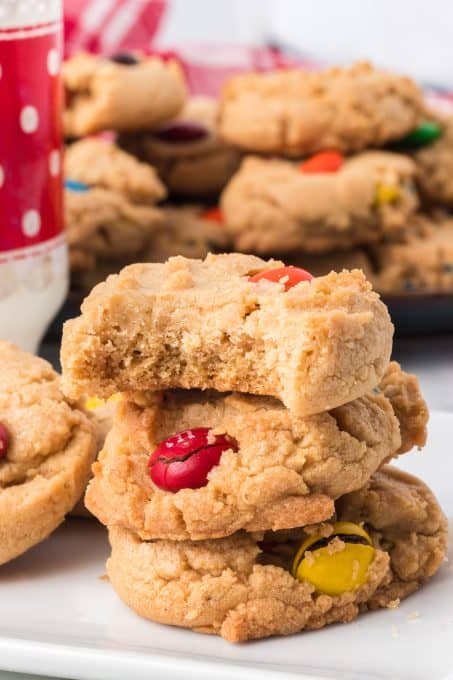 A bite taken out of a peanut butter cookie filled with M&M candies.