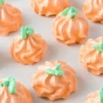 Green stems and leaves decorate pumpkins made of meringue.