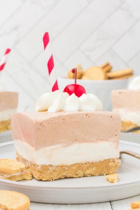 A red and white drinking straw sticking out of a no bake dream bar dessert.