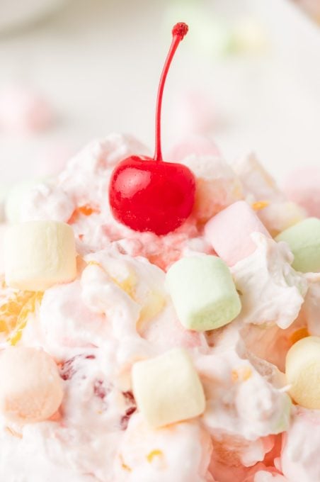 A cherry tops a creamy dessert salad made with marshmallows.
