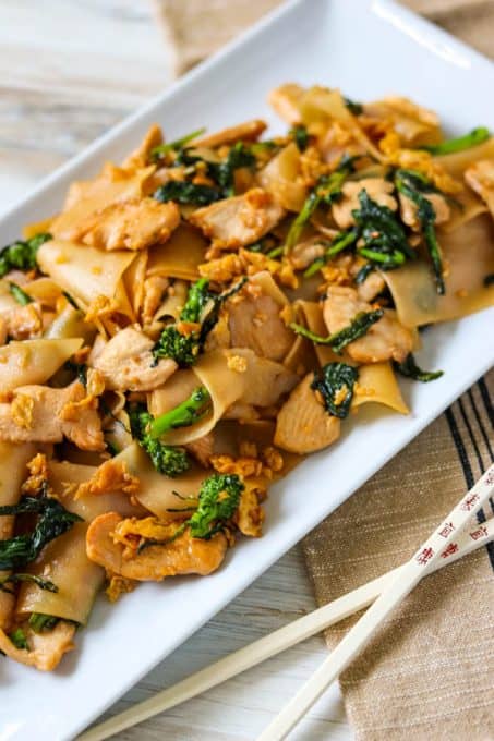 Pad See Ew on a plate next to chopsticks.