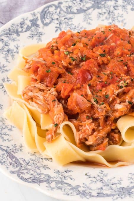 A plate of Pappardelle noodles covered in a red sauce with meat.