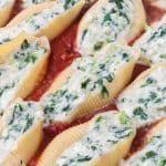 Pasta shells stuffed with ricotta cheese and spinach sitting in a homemade marinara.