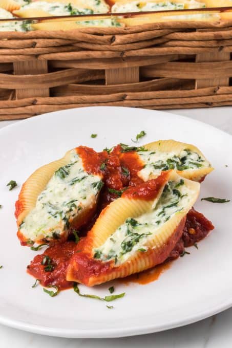 A plate of three stuffed shells with some marinara sauce.
