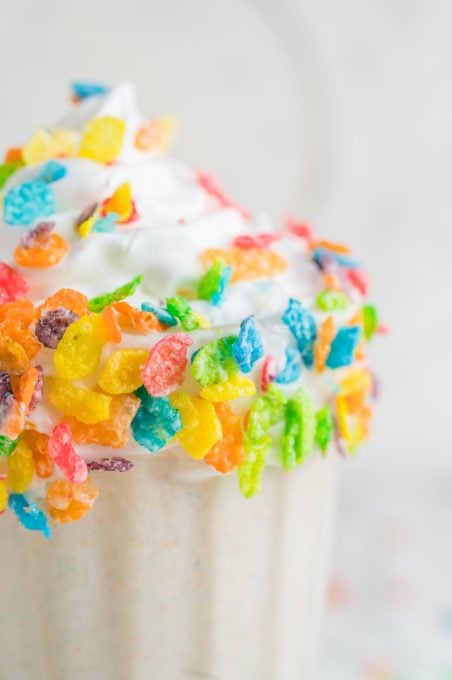 Colorful cereal decorates the rim of a milkshake.