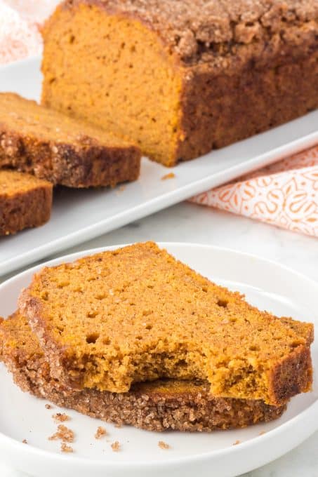 A bite taken out of a slice of pumpkin quick bread.