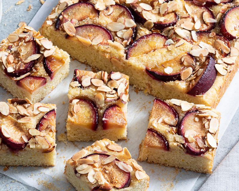 Vanilla Plum Sheet Cake sliced on parchment