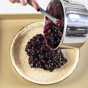 Pouring blueberry filling into crust 