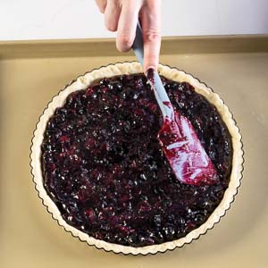 Spreading blueberry filling in crust