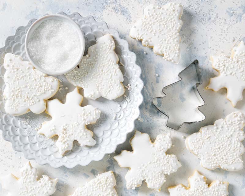 mimosa cutout cookies on white surface with cookie cutters