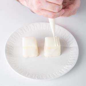 Decorating white petit fours on white plate
