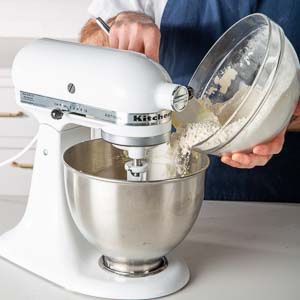 Adding flour mixture to mixer's mixing bowl