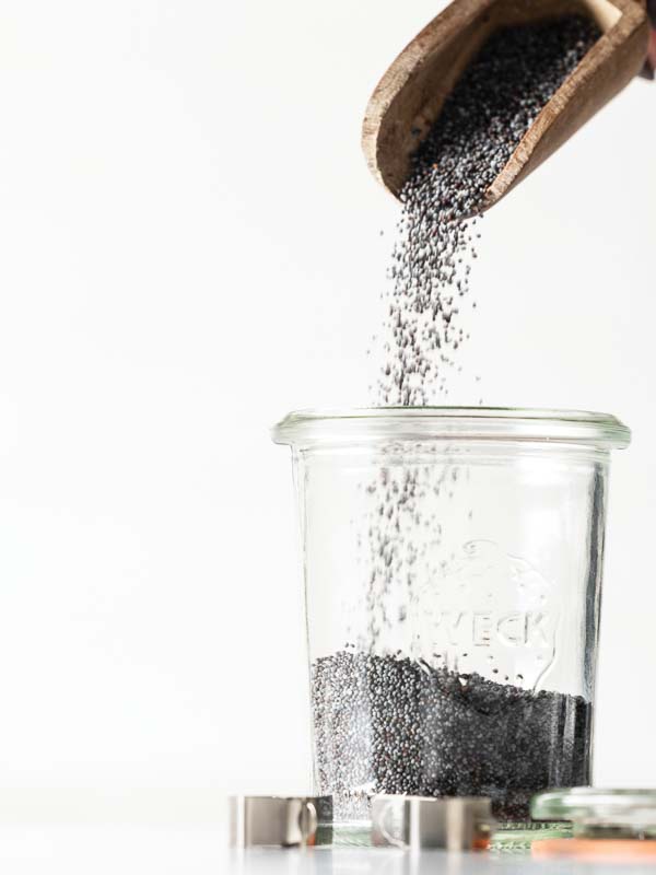 Pouring poppy seeds into a glass jar