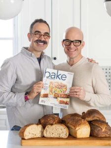 Kevin Masse and Brian Hart Hoffman holding an issue of Bake from Scratch magazine from 2017 with loaves of bread