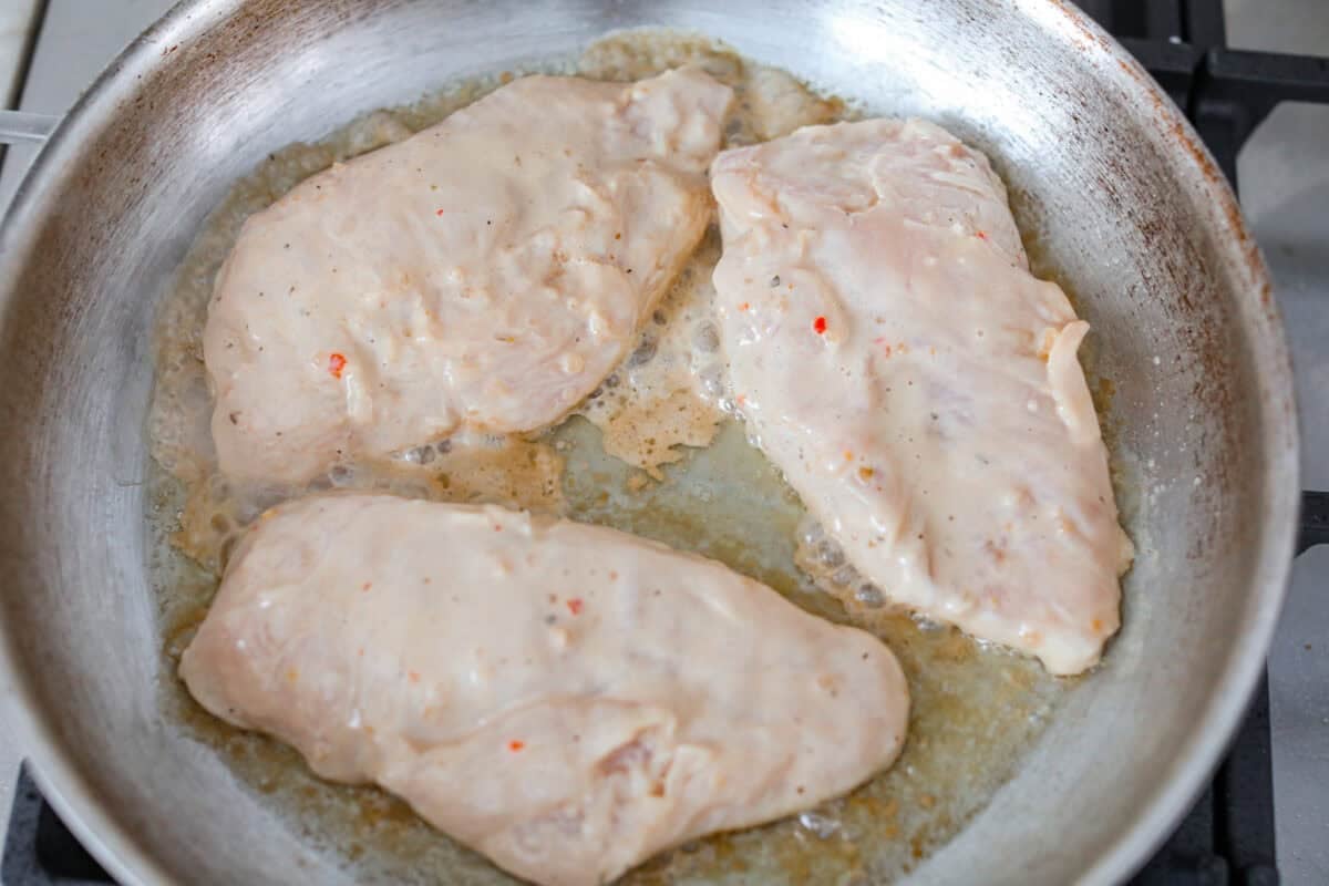 Marinated chicken cooking on a hot skillet.