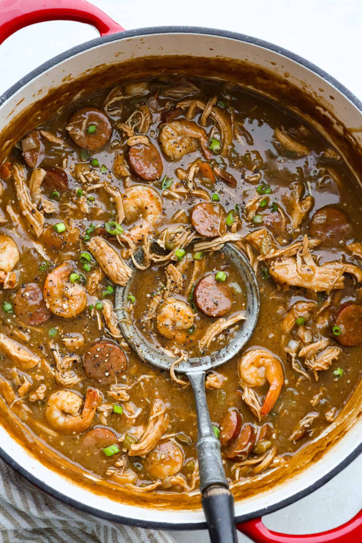 Large pot of New Orleans gumbo with a silver ladle.