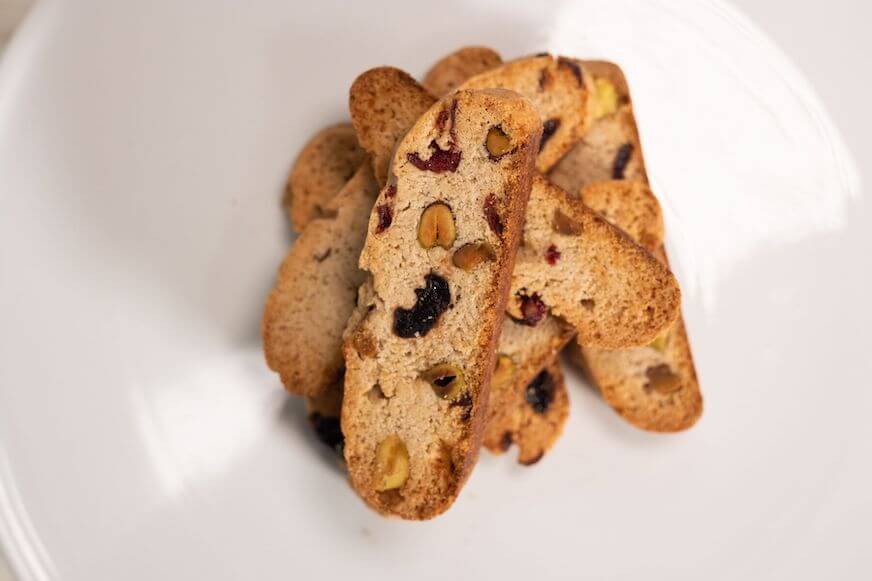 An overhead view of pieces of almond biscotti stacked on a white plate.