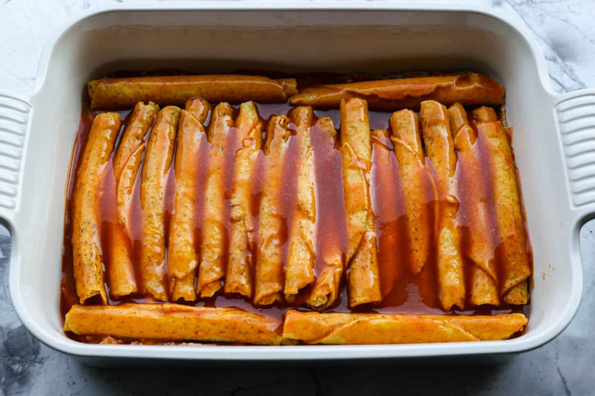 Enchilada sauce spread over the top of the taquitos. 