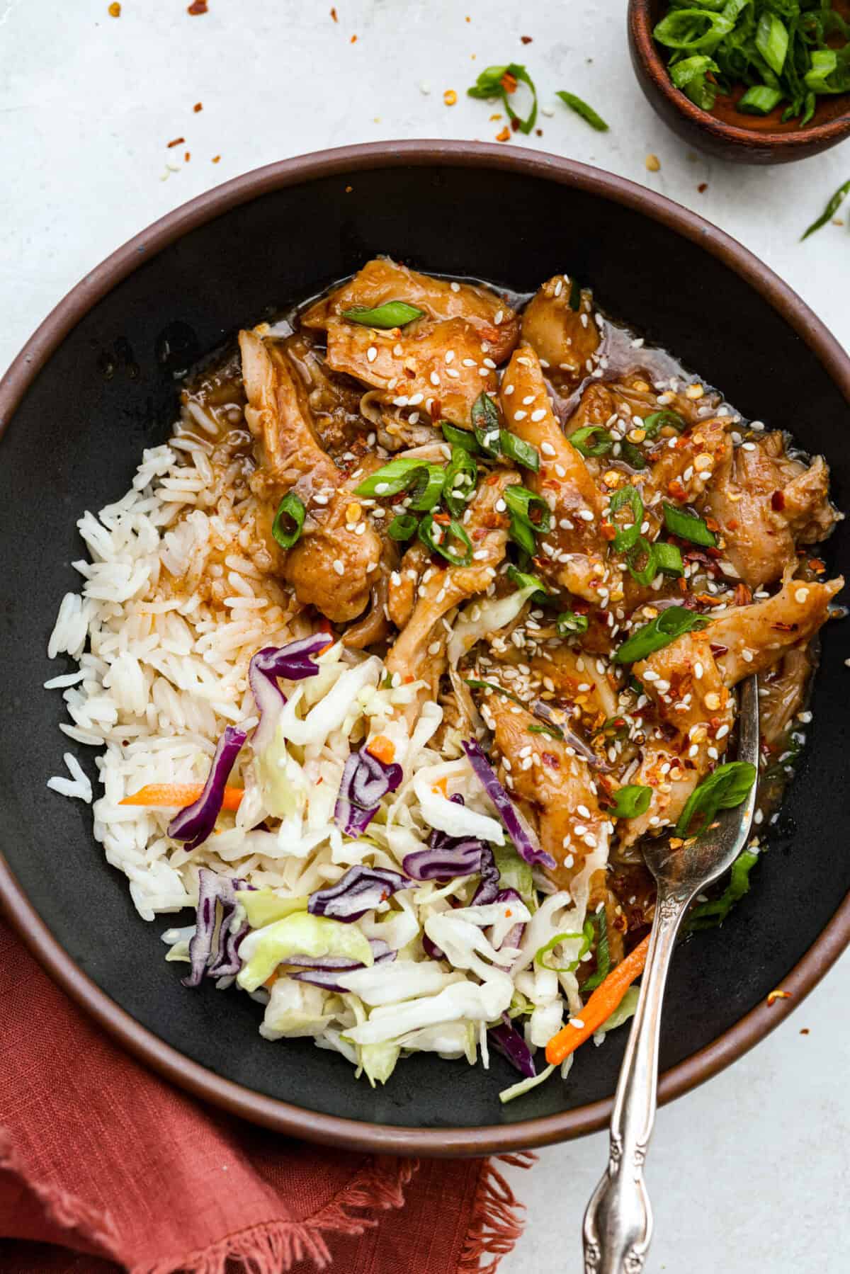 Slow cooker Korean BBQ chicken in a bowl with rice and cabbage. 