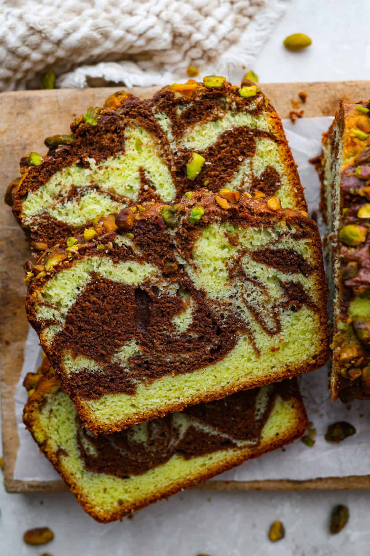 Chocolate pistachio loaf sliced and laying on its' side on a cutting board.