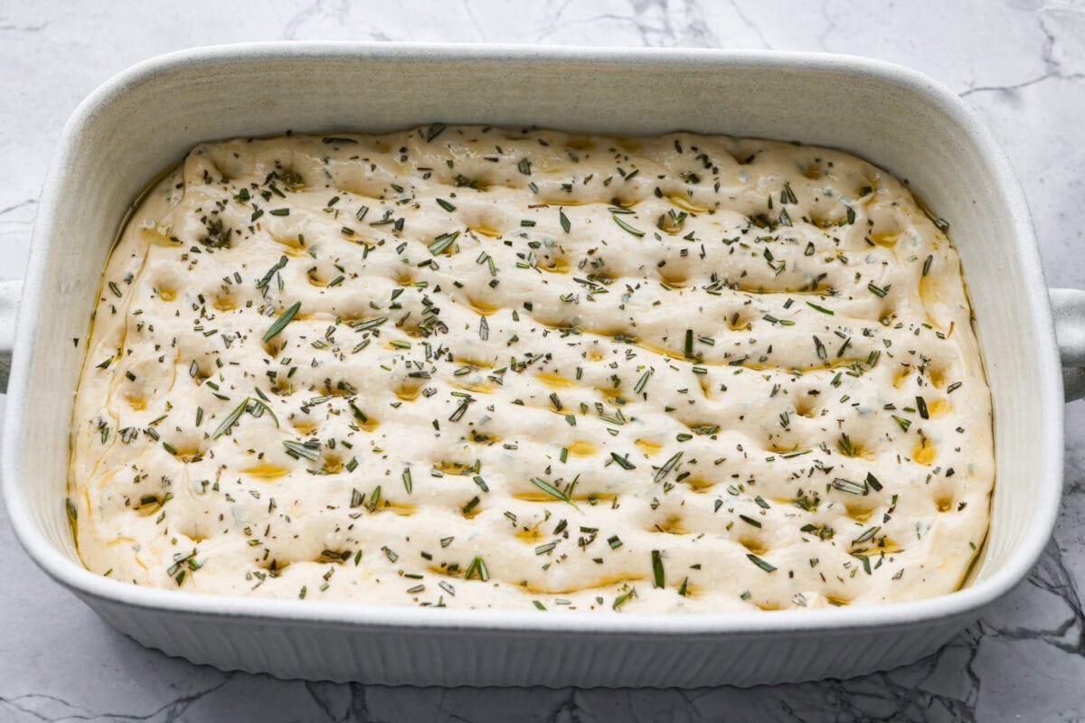Fresh rosemary, olive oil, and salt added to the poked dough.