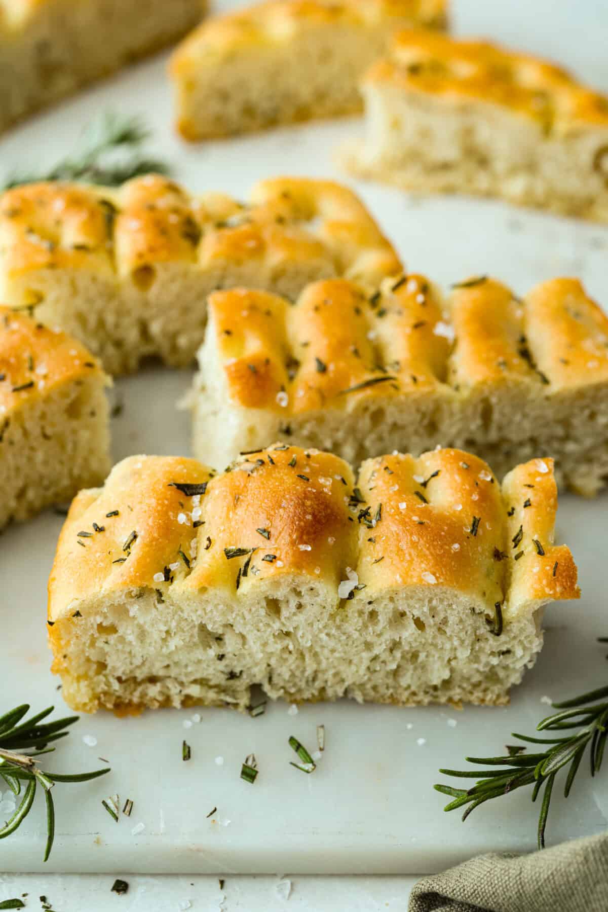 Sliced pieces of rosemary focaccia bread topped with course salt and fresh rosemary. 