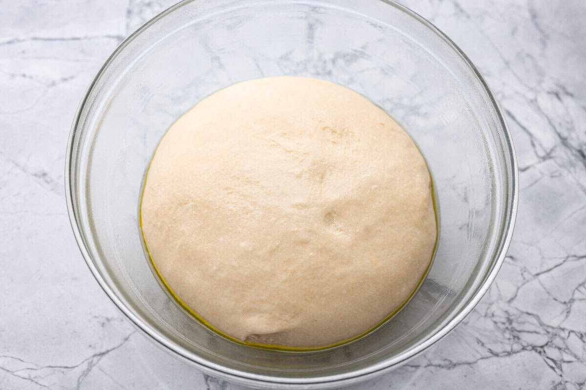 Dough ball in the bottom of a bowl rising.