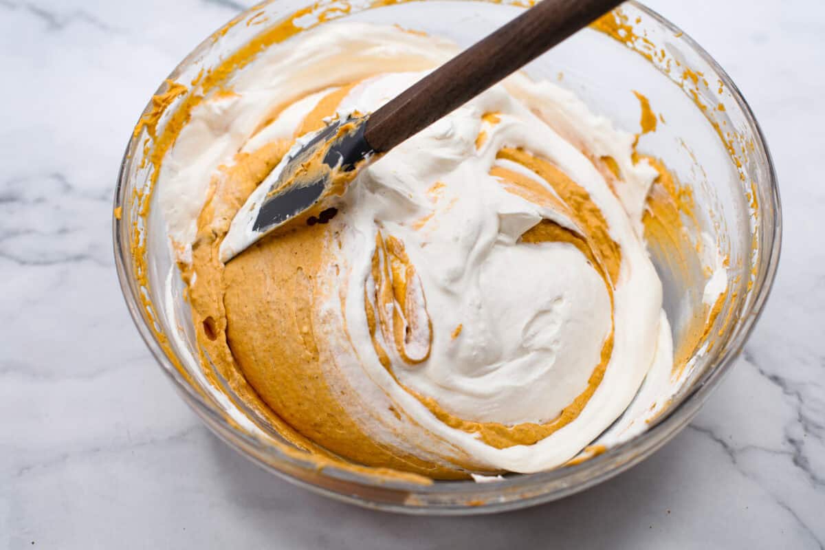 Overhead shot of whipped cream being folded into the pumpkin mixture.