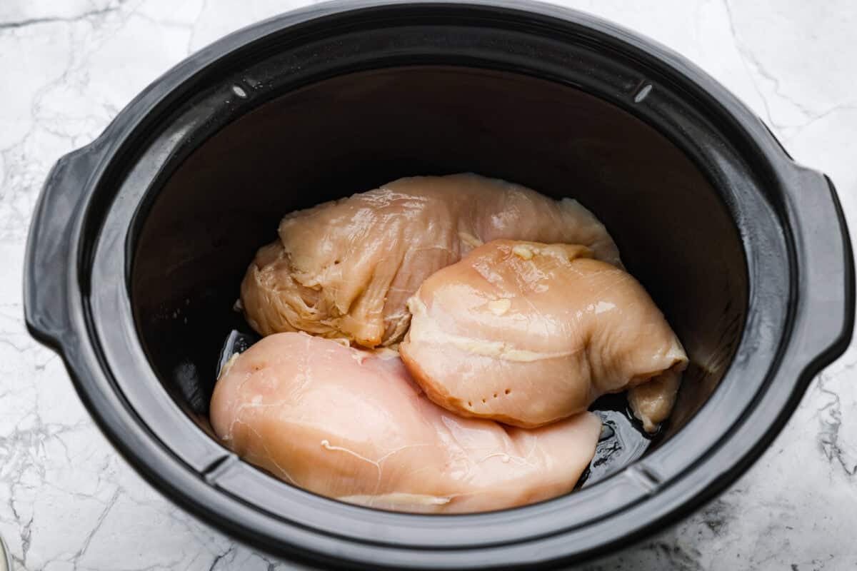 Crockpot with chicken breasts in the bottom. 